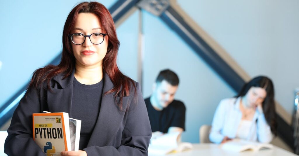 Woman in classroom setting holding Python programming book, with students in background.